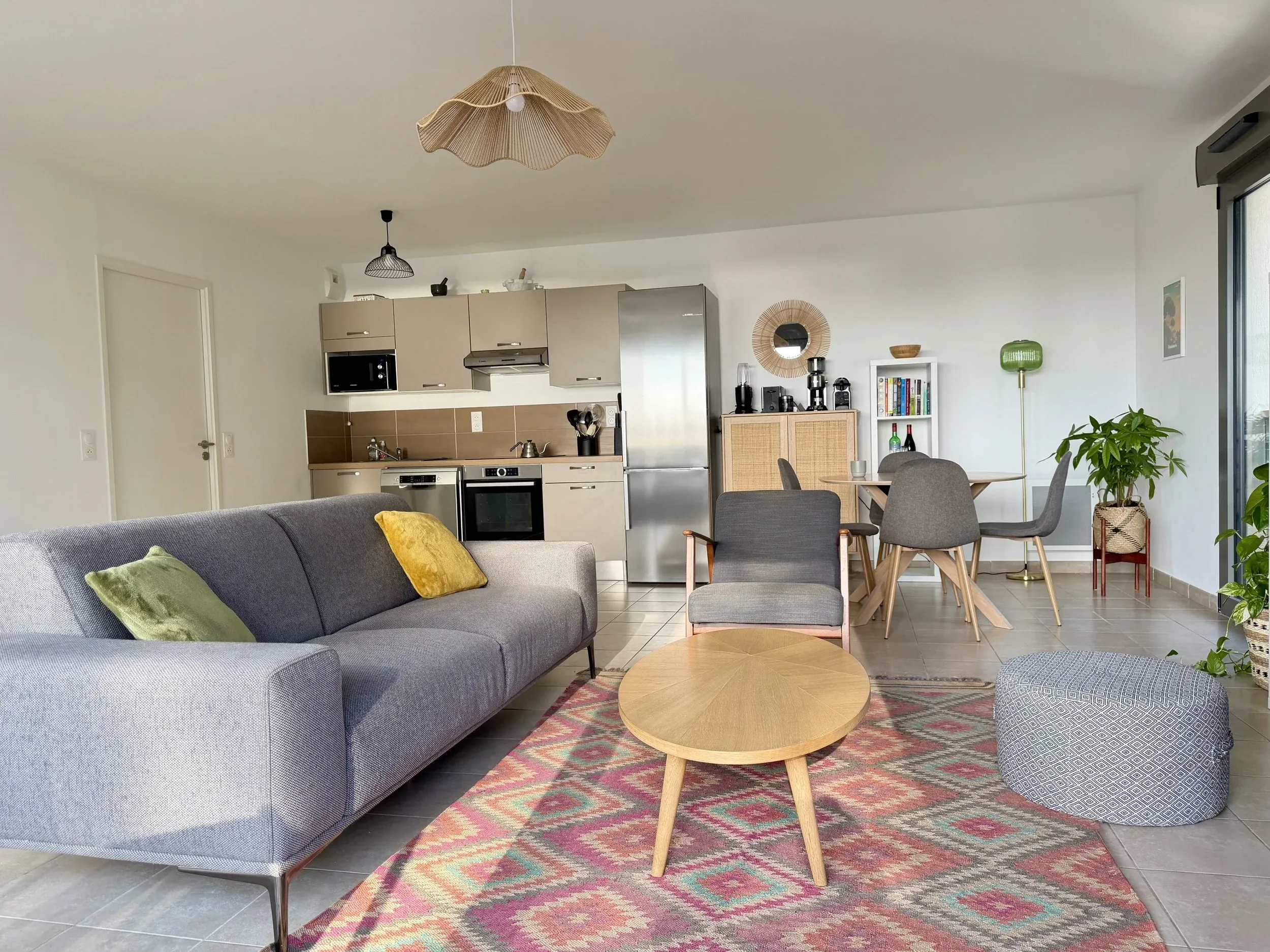 Salon lumineux avec mobilier en bois, canapé gris et plantes